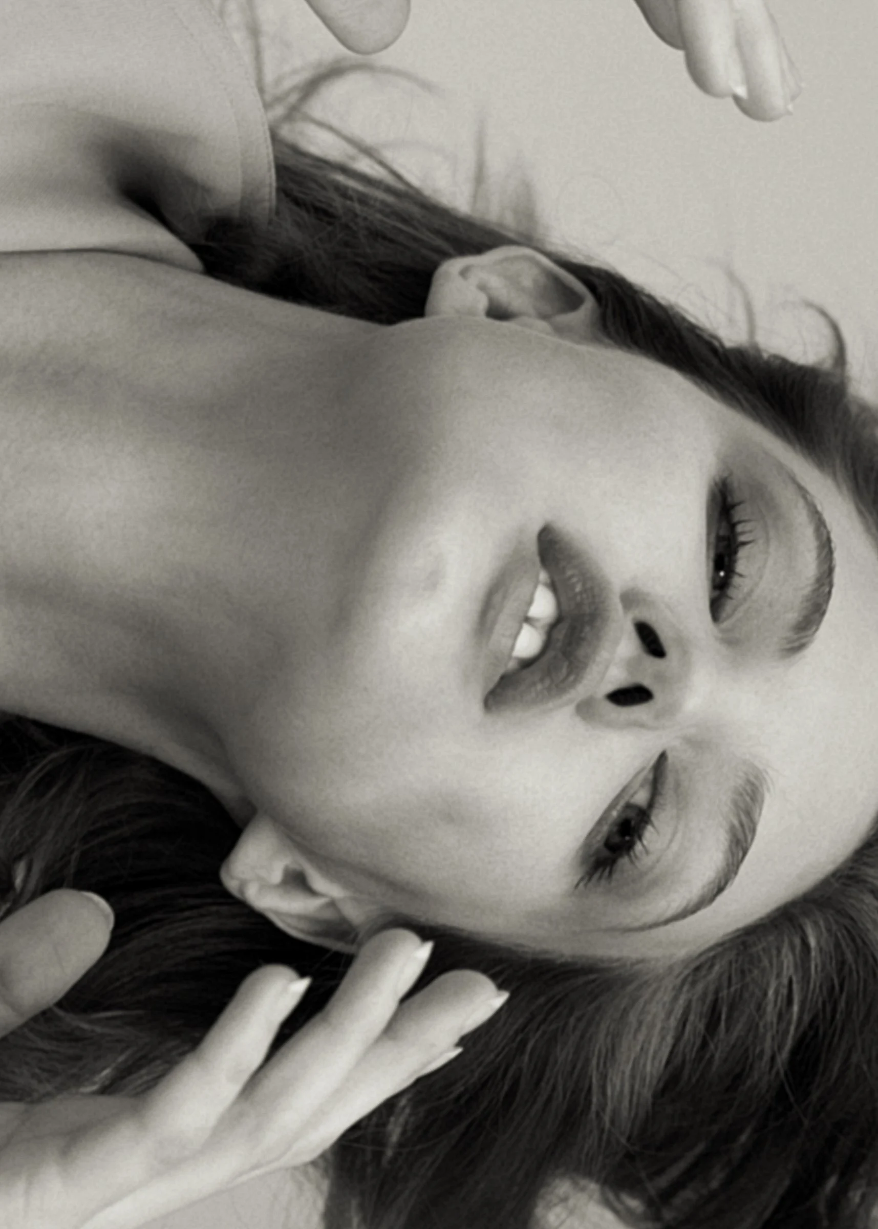 Puss Puss, 2019: black-and-white portrait of a model lying back, hands in her hair
