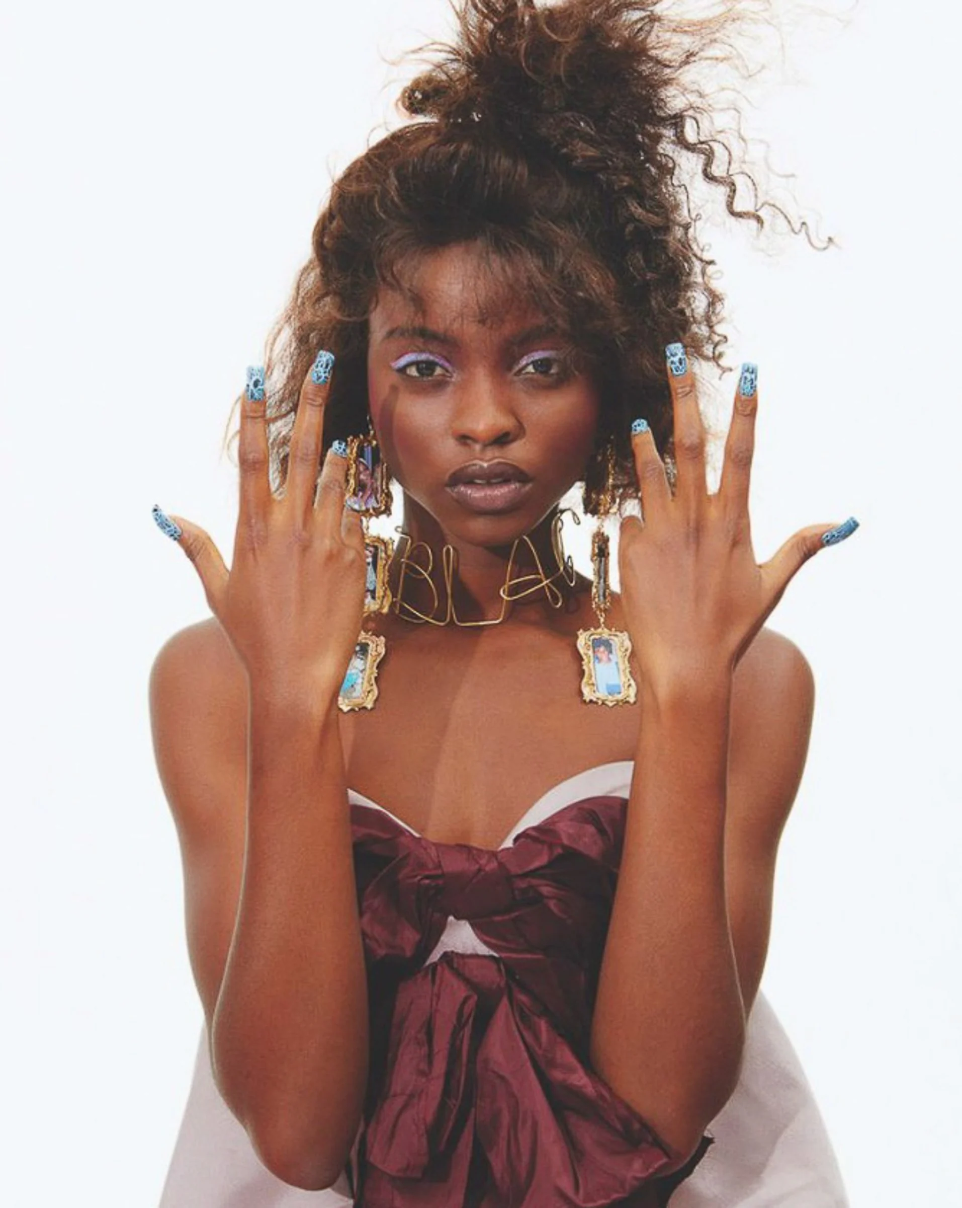 Office, 2019: a model in a red bow top with jewelled nails, hands raised to her face