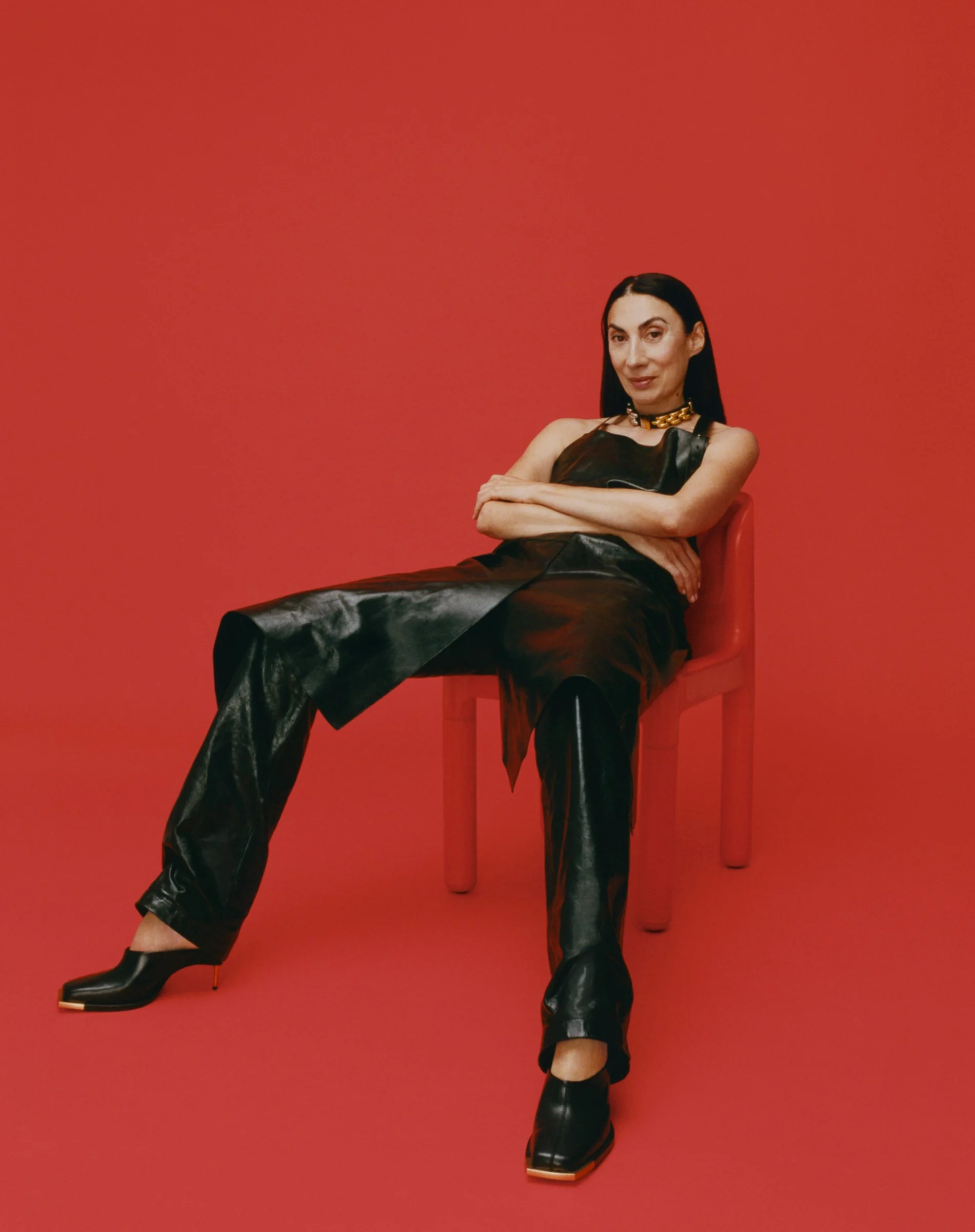 Interview, 2020: a woman in black leather on a red chair against red
