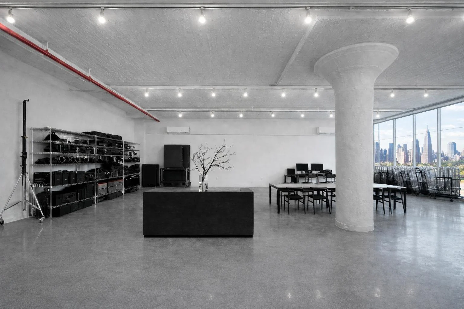 The studio floor: polished concrete, a round column, equipment shelves and the Manhattan skyline through the windows